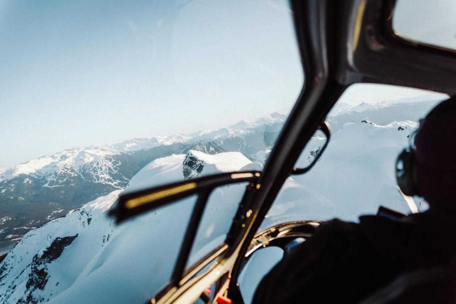 Winter view from a helicopter cabin toward snow-covered ski runs on Whistler Blackcomb