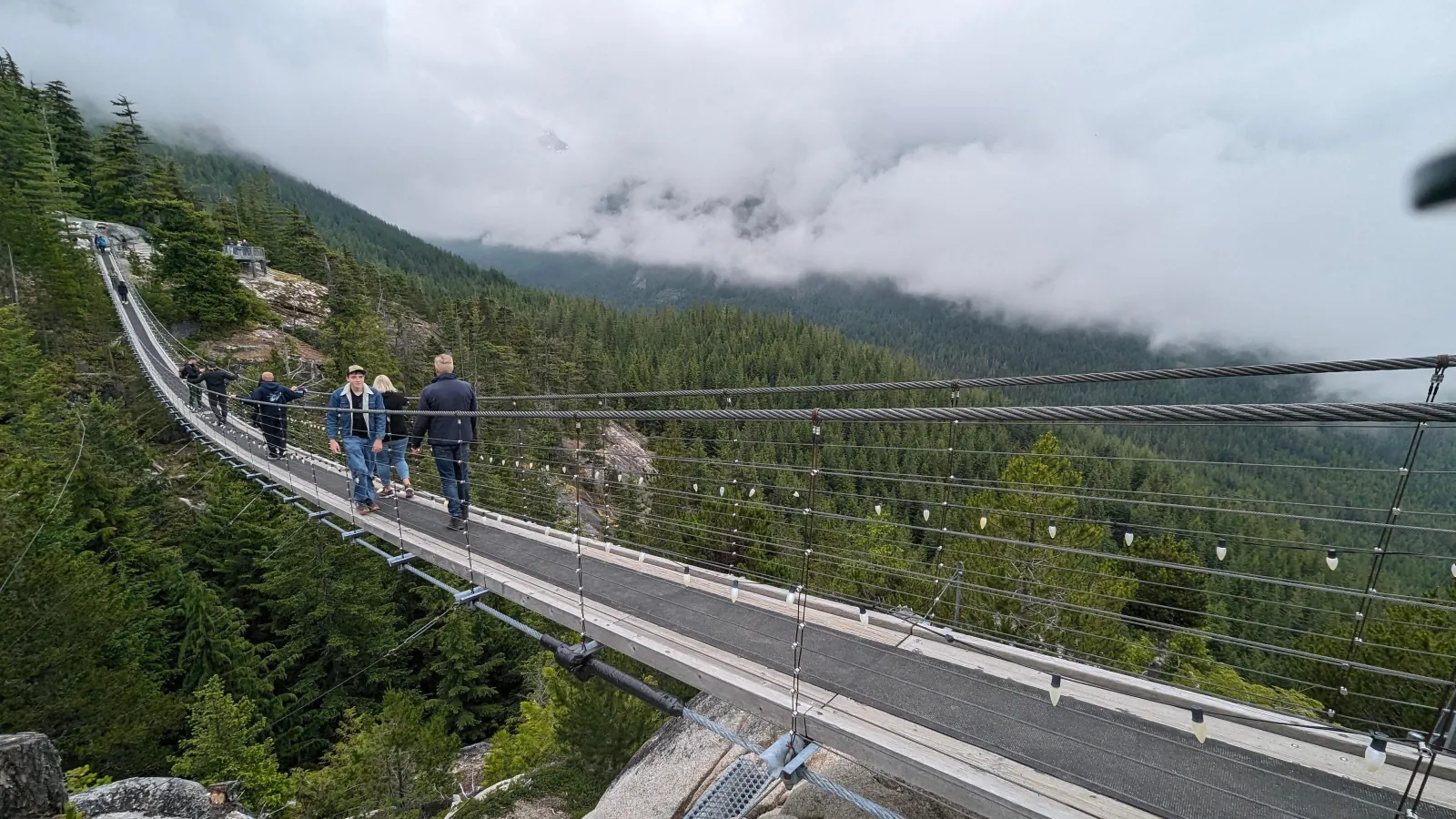 Visitors on the Sky Pilot Suspension Bridge with low cloud over the valley