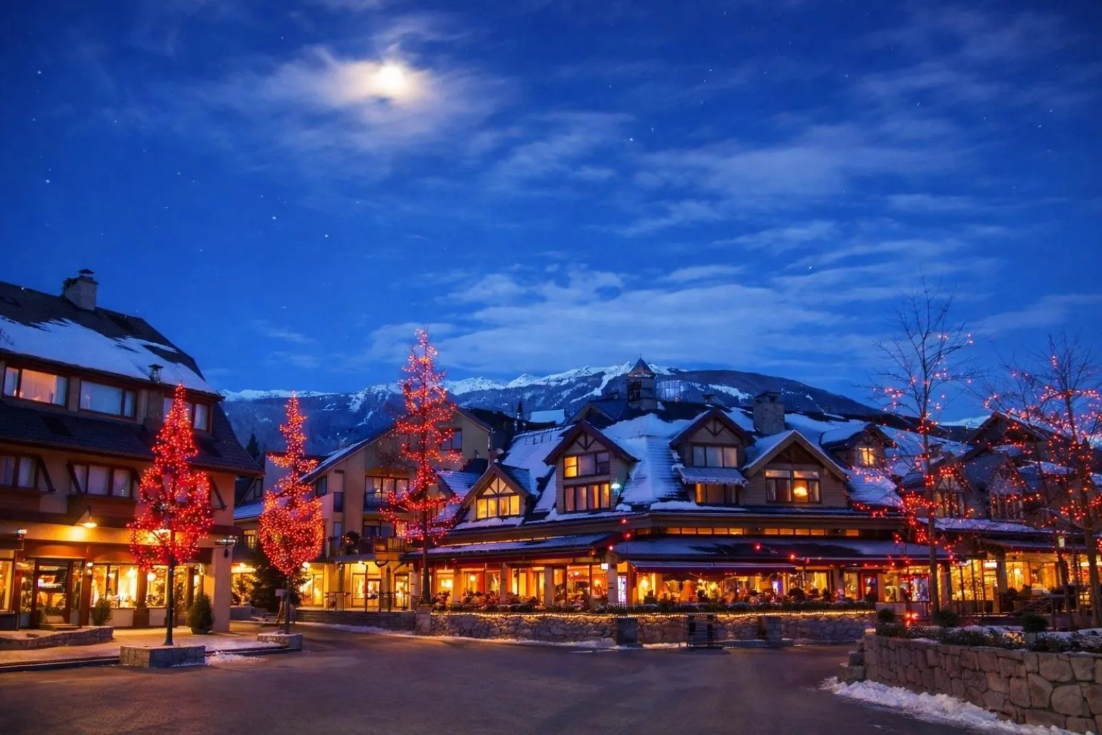 Whistler Village at night in winter with lit trees and snow on the rooftops