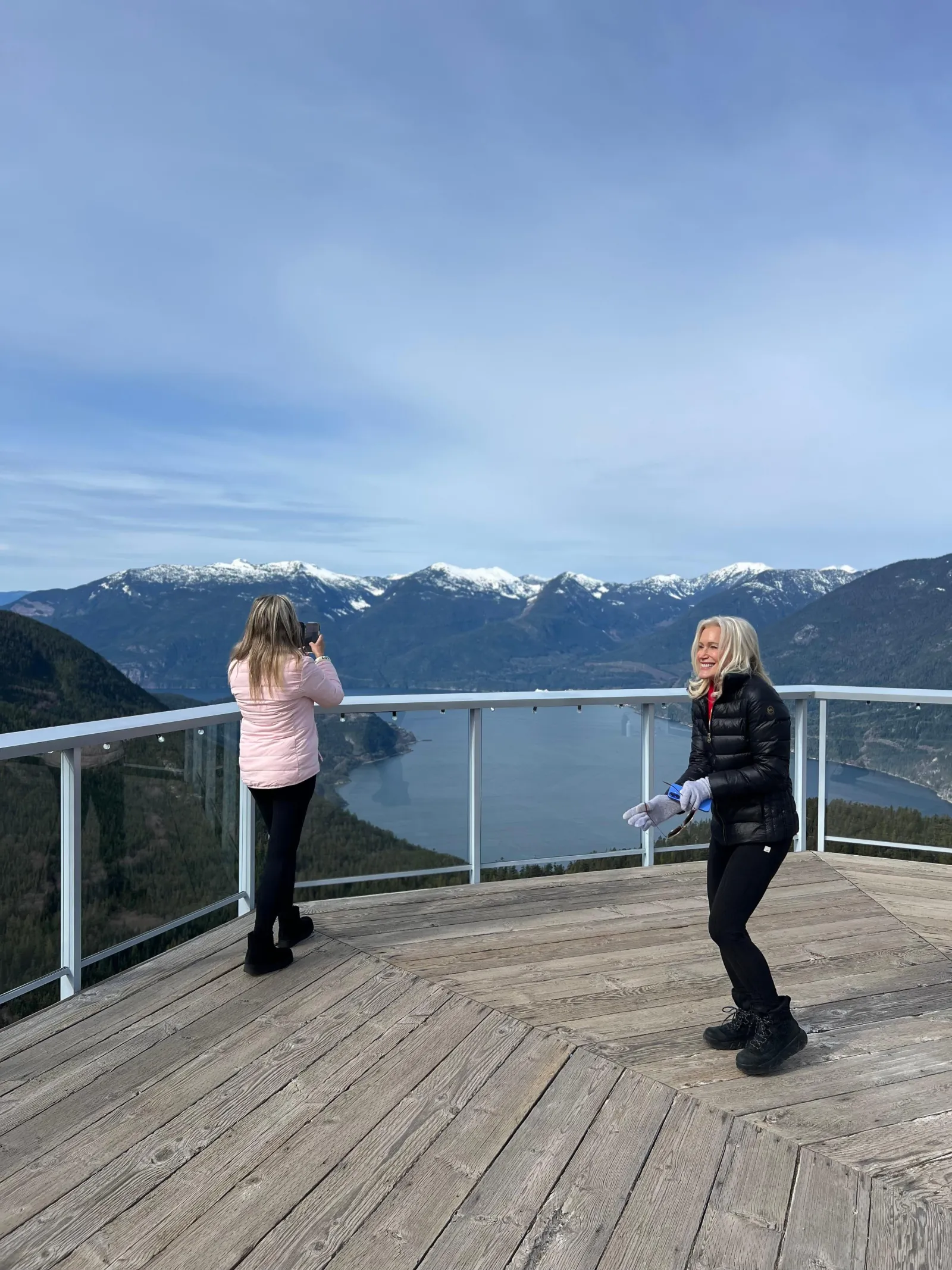 Two visitors on the Summit Lodge deck above Howe Sound on a cool spring day