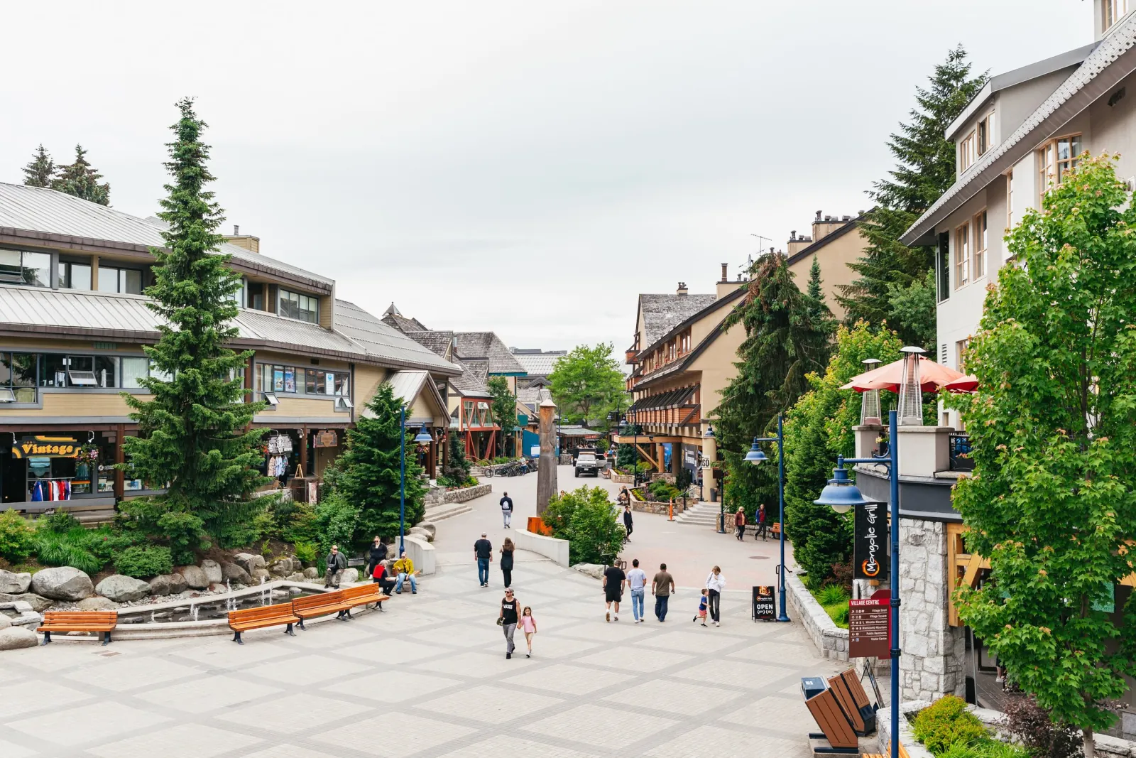 Pedestrian Village Stroll in Whistler Village in summer with shops, benches and trees