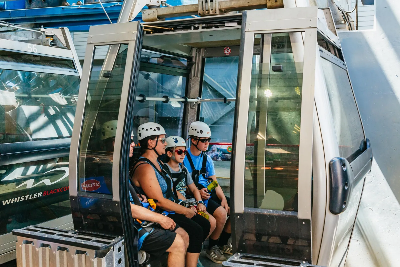 Family in zipline helmets and harnesses seated in a Whistler Village Gondola cabin