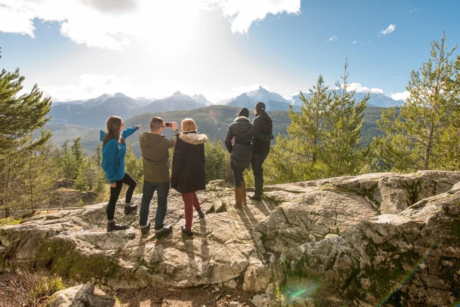 Small group on a rocky lookout facing the snow-capped Tantalus Range