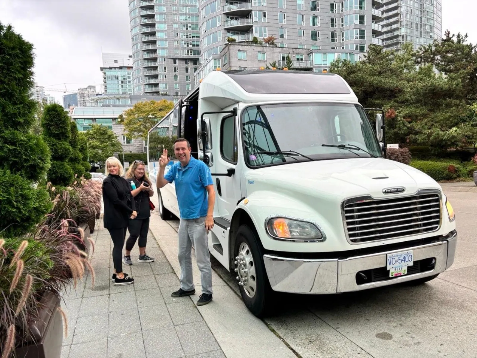 Guide beside a white Landsea mini-coach on a downtown Vancouver street