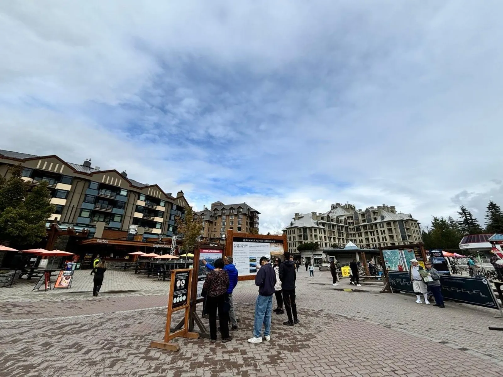 Whistler Village plaza on a cloudy day with visitors reading information boards