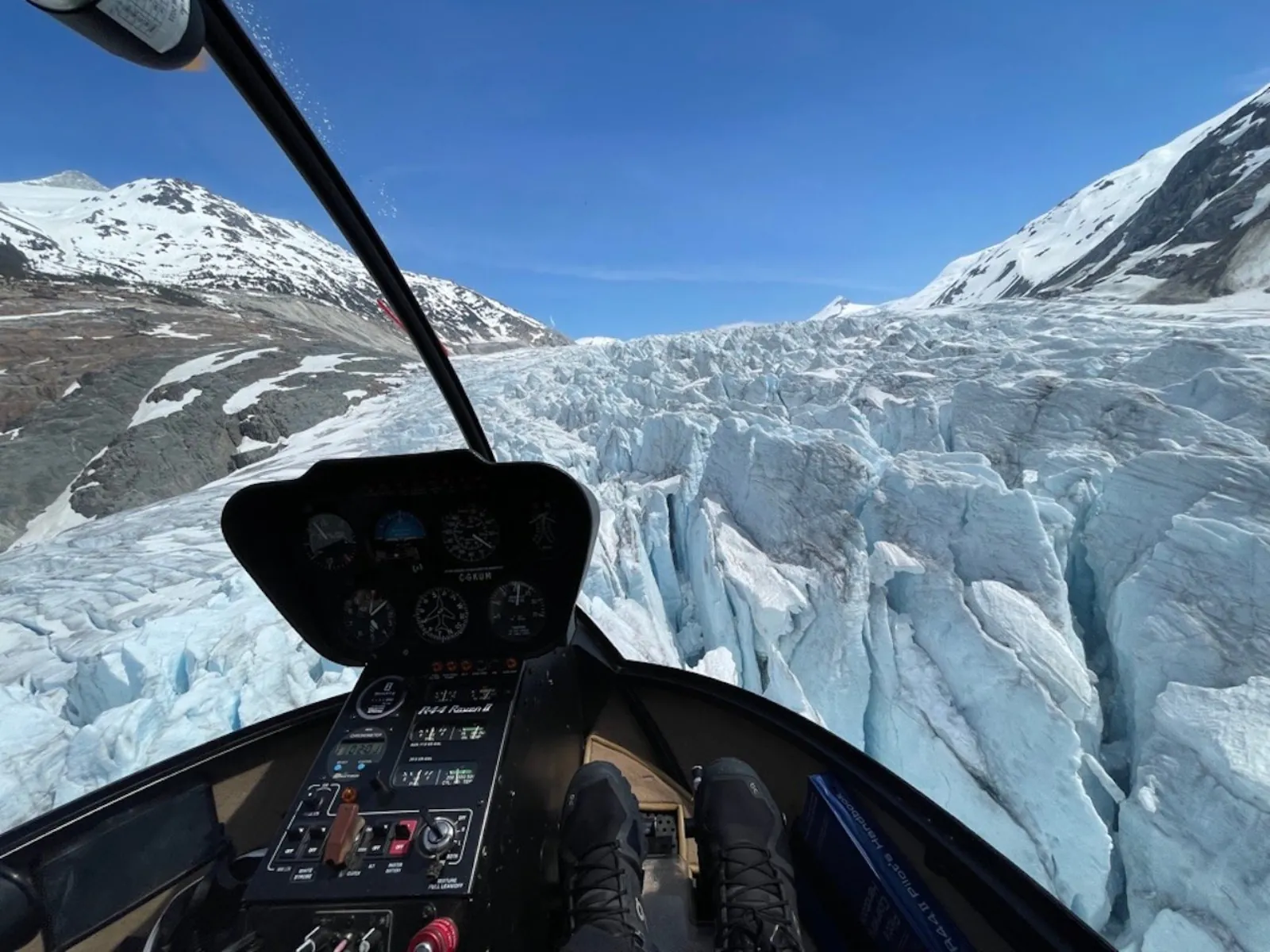 Pilot's-eye view from a small helicopter flying low over a crevassed glacier