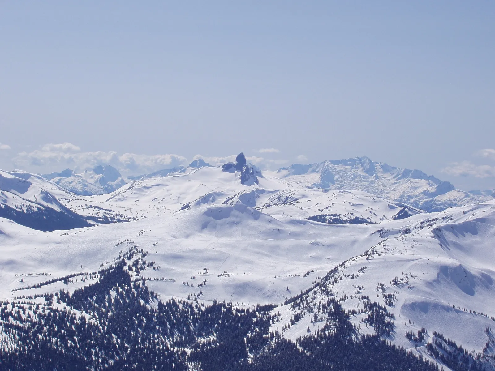 Snow-covered alpine plateau with the dark pinnacle of Black Tusk on the skyline