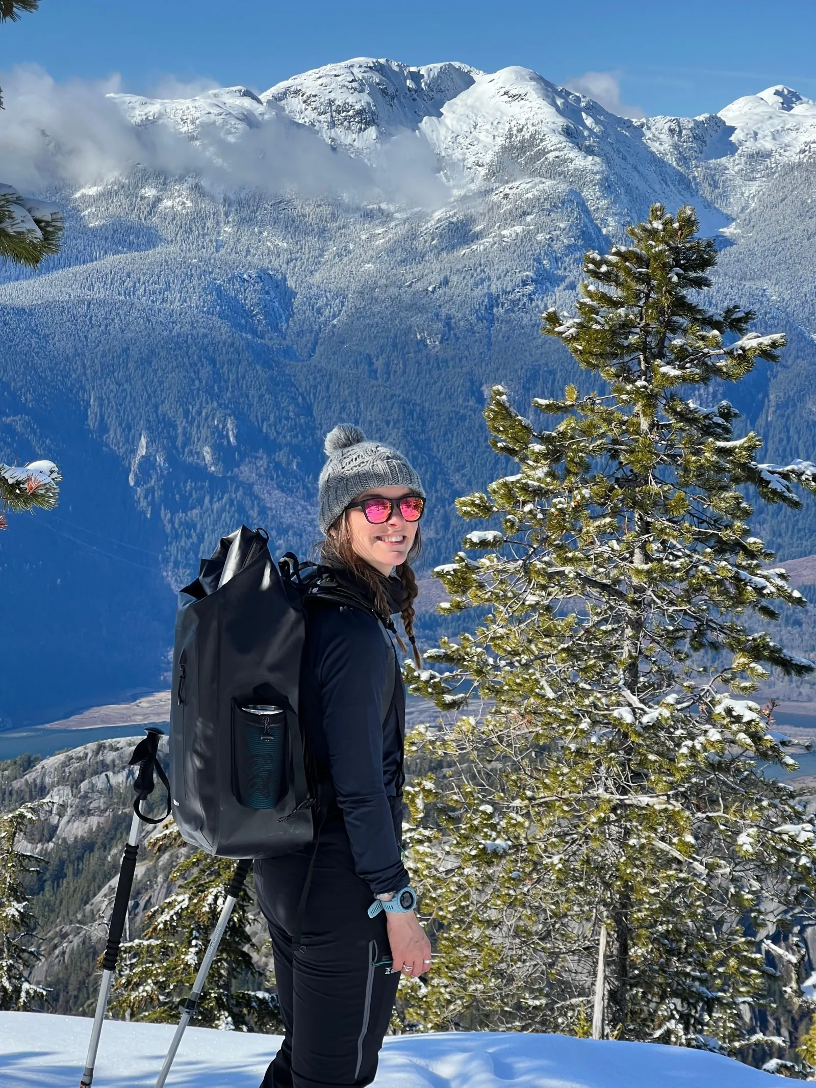 Snowshoer with a backpack above the Squamish valley, the granite Stawamus Chief and snowy peaks behind