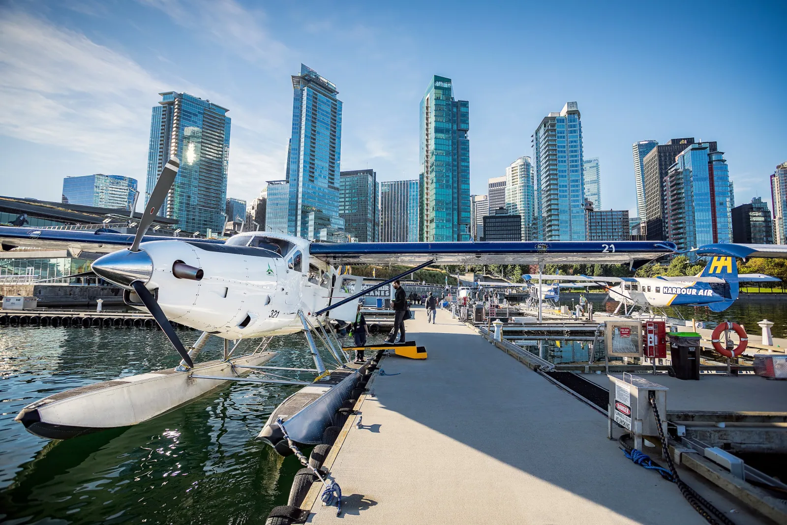 Harbour Air floatplanes docked at the Vancouver harbour terminal below glass towers