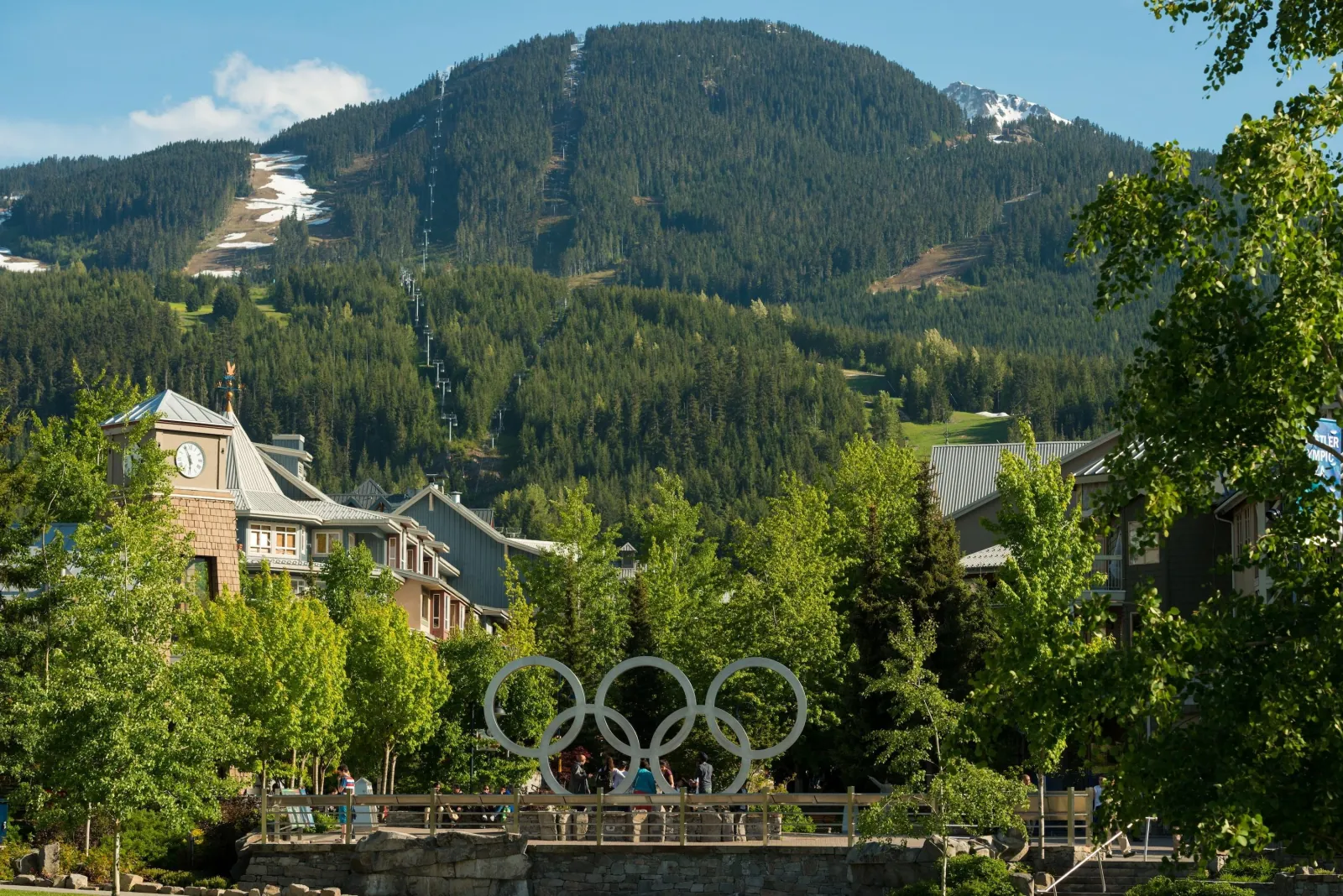 Olympic rings in Whistler Village below the green ski runs of Whistler Mountain