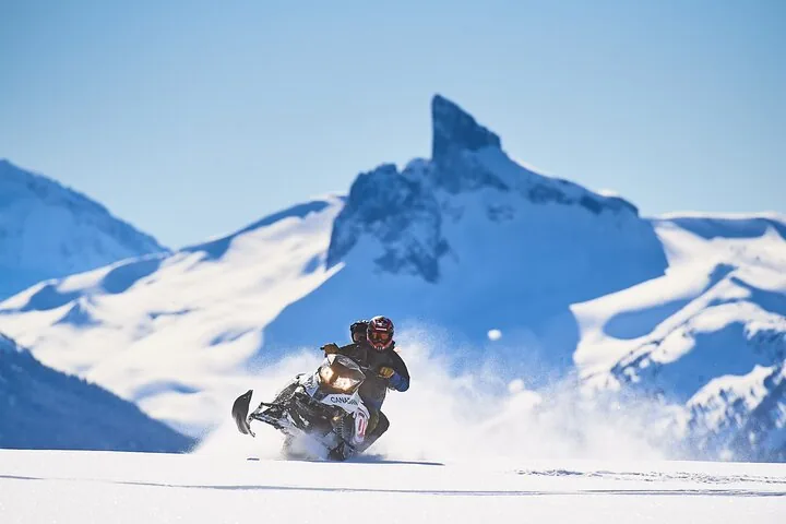 Snowmobile rider in deep powder with the pointed Black Tusk peak behind